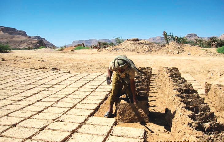 Stacking dried mud-bricks.